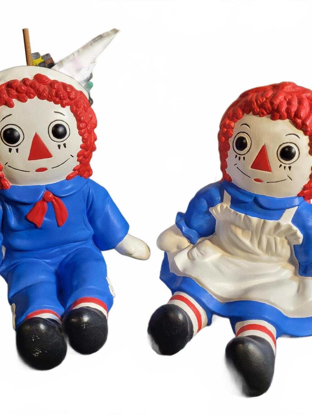 Matching vintage hand-painted ceramic Raggedy Ann and Andy seated figurines.